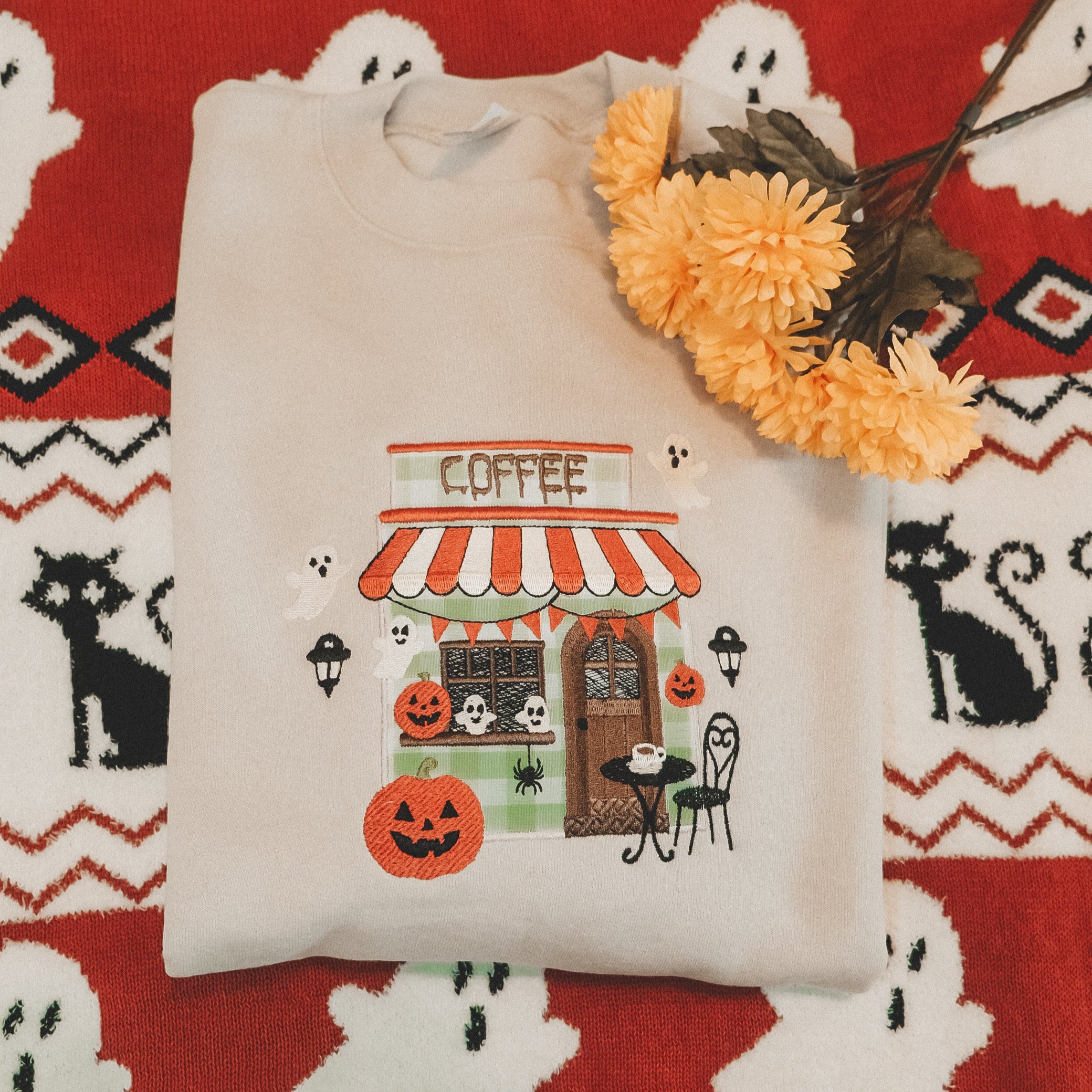 Embroidered sweatshirt with Halloween-themed design on a blanket with ghost patterns.