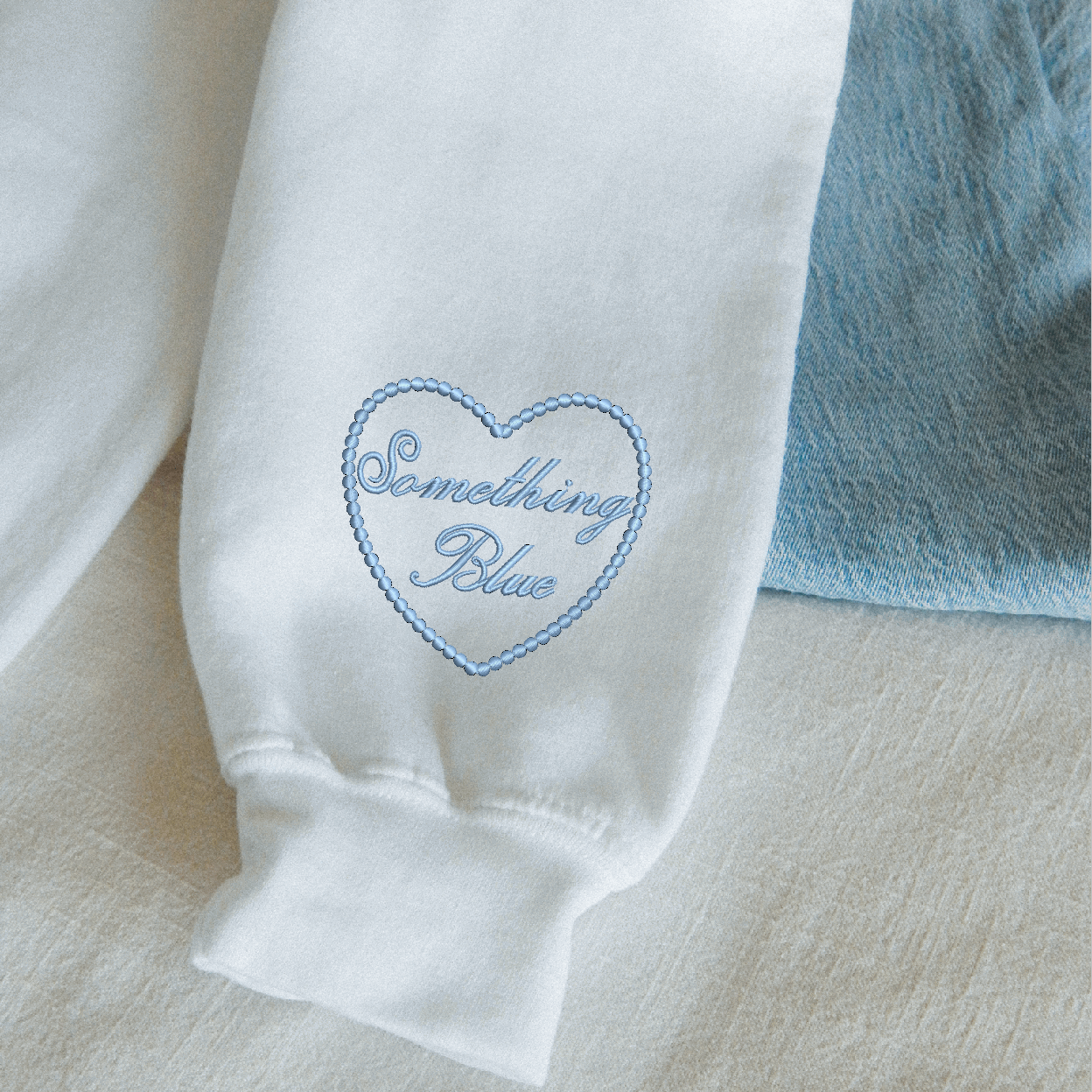 White garment with 'Something Blue' embroidery on a light background
