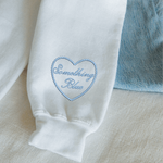 White garment with 'Something Blue' embroidery on a light background