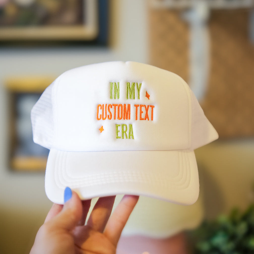 White cap with custom text held by a hand in an indoor setting