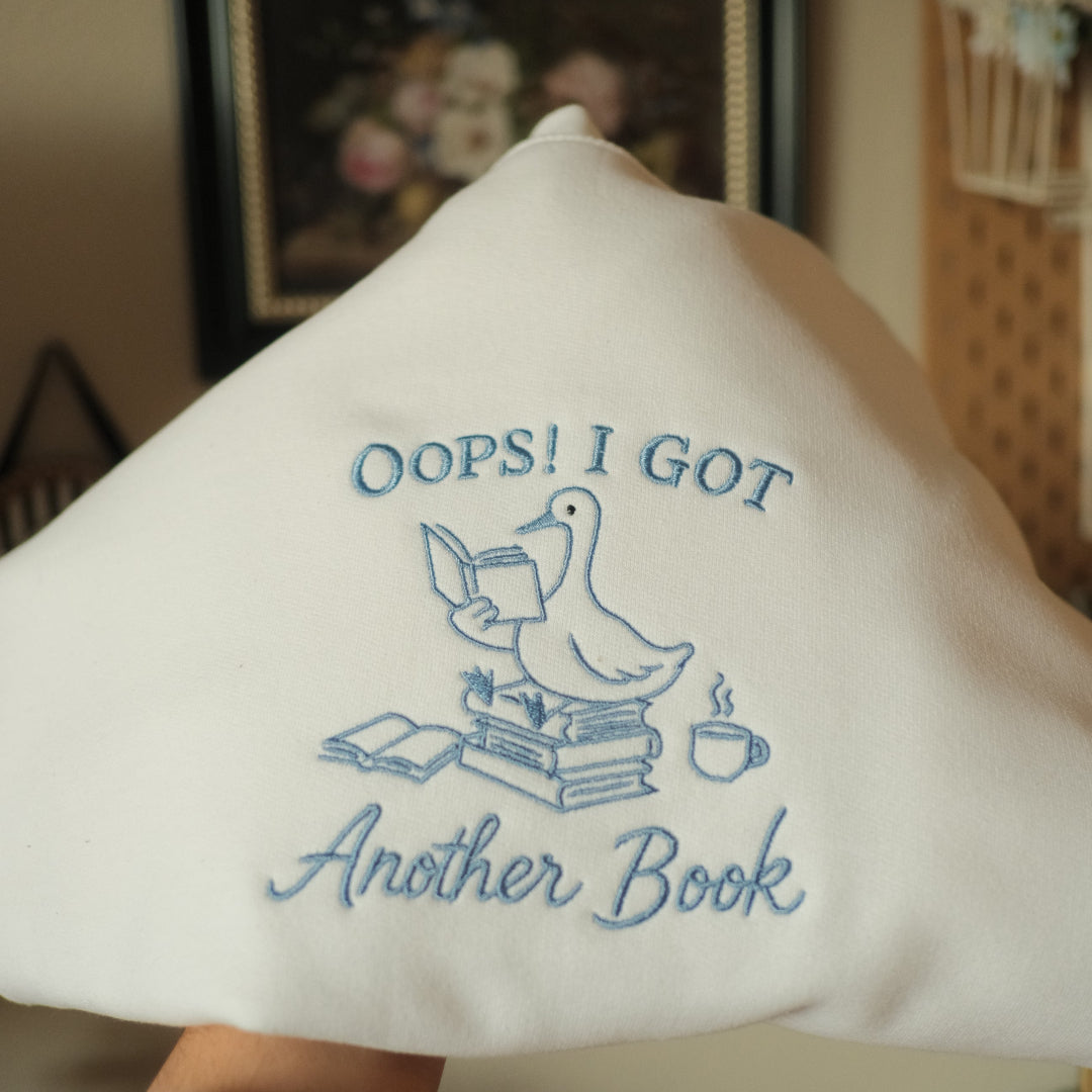 oops i got another book goose on books embroidered on white sweatshirt 